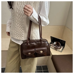 Close-up of brown vintage shoulder bag with double pockets and gold twist-lock detail