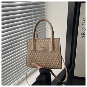 Détail du sac à main matelassé beige avec boucle nœud doré et finitions soignées