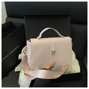 Close-up of pink crossbody bag with wide shoulder strap and luxury gift box packaging