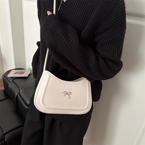 Borsa hobo beige minimalista con fiocco argentato in un ambiente interno di stile