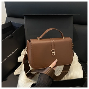 Brown textured small square bag inside a gift box with wide strap and gold hardware