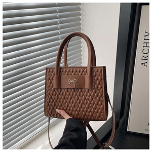 Détail du sac cabas matelassé marron avec nœud doré et texture en similicuir premium