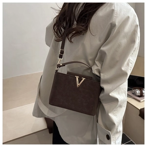 Détail du sac en cuir mat marron foncé avec boucle métallique dorée élégante en V