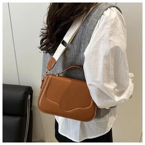 Detail of caramel PU leather crossbody bag with wave texture and wide woven strap