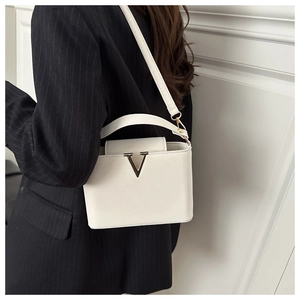 Détail du sac à bandoulière crème avec boucle dorée en V et design structuré