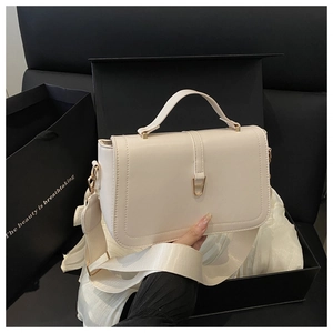 Close-up of cream crossbody bag with gold D-buckle and fabric strap in gift box