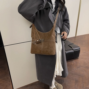 Brown suede hobo tote with cat-shaped stitching and adjustable strap on model