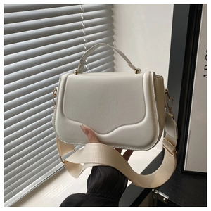 Detail of elegant cream shoulder bag with wave stitching and golden hardware