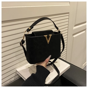 Détail du sac seau noir avec logo V en métal doré et texture en daim mat et doux