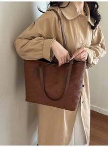 Détail d'un grand sac cabas marron foncé à texture plissée avec un trench beige