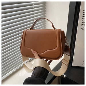 Detail of a brown leather shoulder bag featuring unique streamlined stitching and gold hardware