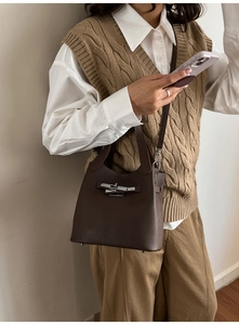 Detail of dark brown lychee grain leather bucket bag with silver twist lock and strap