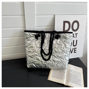 Close-up of silver quilted tote bag with star patterns and black rope handles