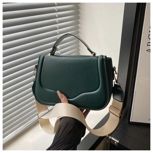 Detail of dark green matte leather bag featuring a wavy edge flap and golden hardware