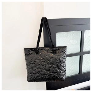 Detail of black star-quilted tote bag featuring woven rope handles and silver eyelets
