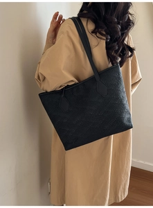 Gros plan d'un grand sac cabas noir avec texture tissée géométrique et anses en cuir