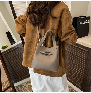 Détail d'un sac seau en cuir taupe avec fermoir rotatif argenté et bandoulière chic