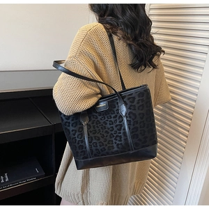 Detail of leopard print tote bag with gold metal logo and black leather shoulder strap