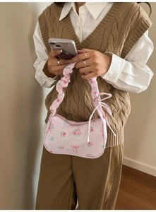 Detail of pink quilted handbag with floral print and scrunchie handle on model