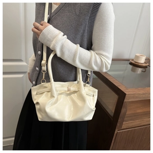 Détail du sac seau crème avec texture plissée élégante et finitions dorées brillantes