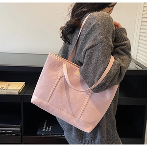 Close-up of pink large tote bag in faux suede shown on shoulder for size reference