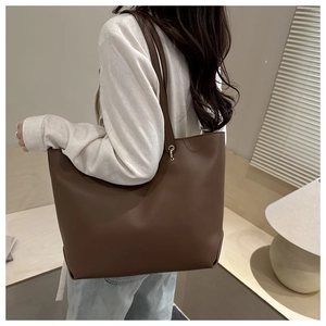 Detail of the large brown tote bag with glossy finish and gold metal hardware