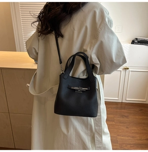 Détail du sac seau en cuir grainé noir avec boucle métallique argentée sur un modèle