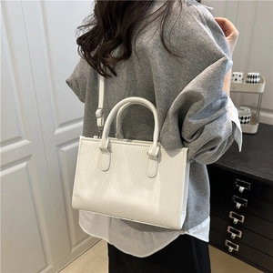 Minimalist white square crossbody bag with vertical striped texture and curved top handle