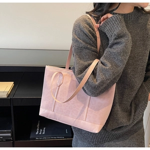 Rosa Shopper mit Tiermuster unter dem Arm getragen, kombiniert mit grauem Strickpullover