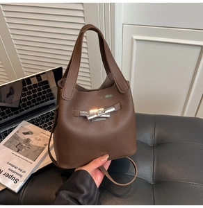 Detailed view of dark brown bucket bag with silver twist lock and pebble grain leather