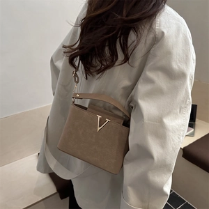 Sac à main structuré marron clair chic avec logo V doré présenté dans un style de vie