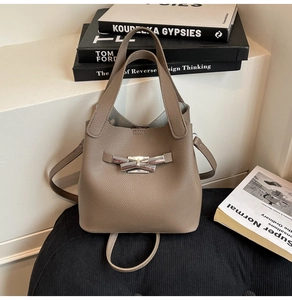 Detail of taupe bucket bag with lychee texture and silver bow-shaped metal lock
