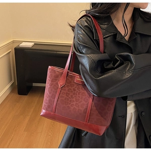 Detail of red-brown tote bag featuring leopard animal print texture and fashion metal plate