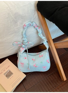 Detailed top view of light blue quilted shoulder bag with pink floral and bow patterns