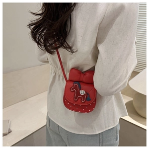 Détail du mini sac carré rouge avec un grand nœud et broderie sur bandoulière fine