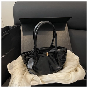 Détail d'un sac seau noir brillant avec boucle dorée dans un élégant coffret cadeau chic