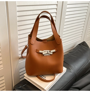 Detail of caramel leather bucket bag featuring silver twist lock on white books