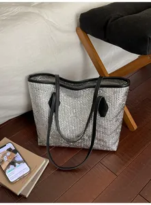 Détail du sac fourre-tout argenté avec texture plissée et anses noires en décor intérieur