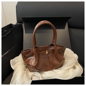 Détail du sac seau marron glacé avec boucle dorée présenté dans un coffret cadeau