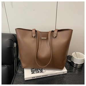 Close-up of brown tote bag with smooth matte texture and golden metal bar detail