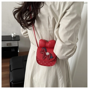 Détail du sac à bandoulière rouge avec broderie cheval et grand nœud sur trench beige