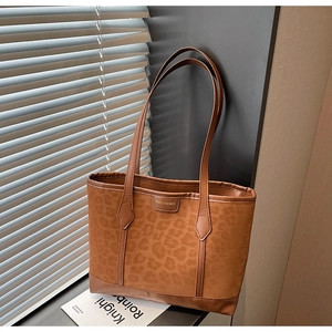 Detail der Totebag mit Leopardenmuster und Metallplakette auf mattierter Oberfläche