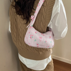 Pink floral underarm bag with bow pattern and textured bubble fabric shown on a shoulder