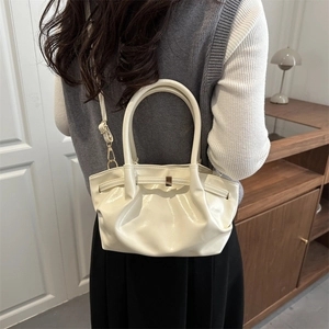 Sac seau plissé crème chic avec détails dorés porté en bandoulière par un mannequin