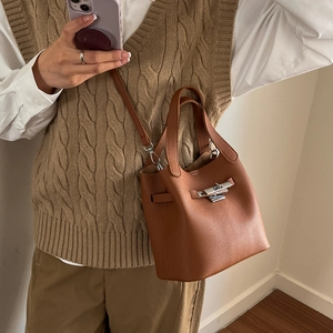 Brown lychee leather bucket bag with silver clasp shown on a model for spring 2026