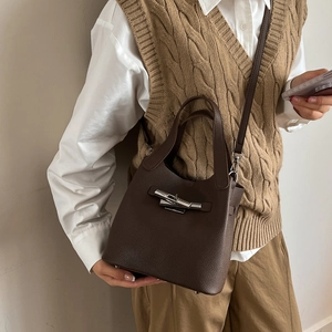 Sac seau en cuir marron foncé avec fermoir argenté porté sur une tenue décontractée