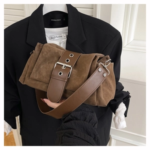 Detail einer braunen Wildleder-Schultertasche mit Metallschnalle und Falten an der Seite