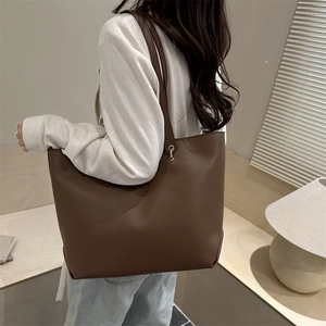 Brown minimalist PU leather tote bag for women shown in a modern home interior setting
