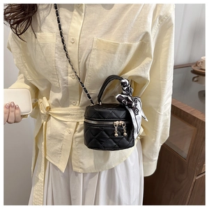 Close-up of black quilted mini bag with golden hardware and decorative silk scarf