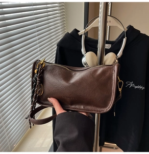 Macro detail of dark brown retro shoulder bag with gold metal zipper and brand embossing
